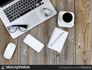 Desktop with modern technology, paper and pen and dark coffee ready for work. High angled view with vertical rustic wooden boards.