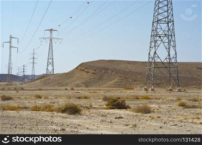 Desolate infinity of the Rocky hills of the Negev Desert in Israel. Electrical power lines on pylons in the landscape of the Middle East