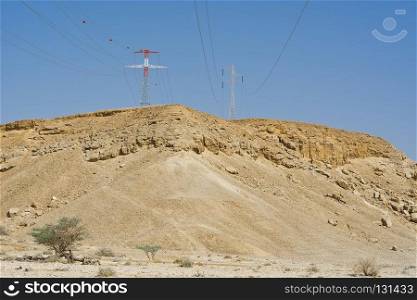 Desolate infinity of the Rocky hills of the Negev Desert in Israel. Electrical power lines on pylons in the landscape of the Middle East