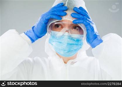 Desperate medical NHS EMS worker in white protective suit,blue surgical mask latex gloves   safety goggles,Coronavirus COVID-19 pandemic crisis causing shortage of protective personal equipment supply