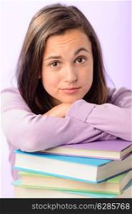Desperate student girl leaning on stack of books purple background