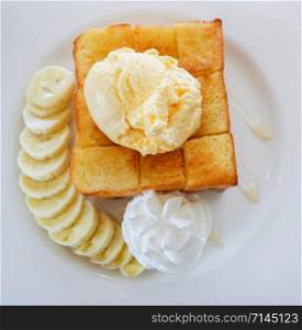 Dessert bread honey santos vanilla ice cream with whip cream banana fruit and honey bee on white plate in the cafe coffee shop