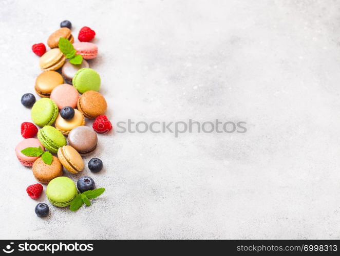 Dessert cake macaron or macaroon with raspberry and blueberry on stone kitchen background . Top view.