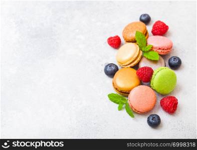 Dessert cake macaron or macaroon with raspberry and blueberry on stone kitchen table background background. Top view.