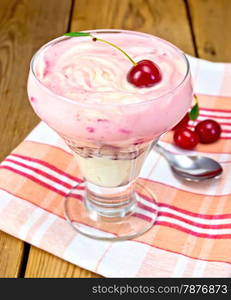 Dessert dairy with cherries and cream curd, spoon on a napkin with cherries on a wooden boards background