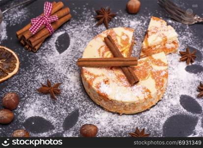dessert from cottage cheese and pumpkin sprinkled with powdered sugar on a black background, top view