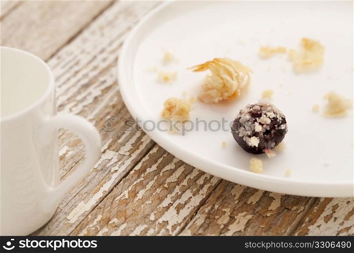 dessert gone - crumbs of cherry cheese danish pastry on white plate with espresso coffee cup on grunge wood table