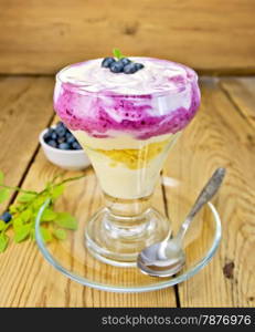 Dessert milk with blueberry, cornflakes, curd, spoon in a glassware on a wooden boards background