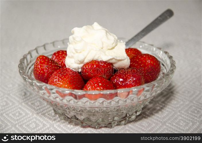 Dessert of fresh strawberries with whipped cream in a glass bowl