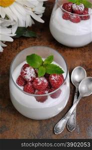 Dessert of whipped cream with raspberries and mint in a glass