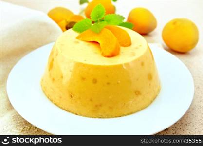 Dessert panna cotta cheesecake with apricots in a plate, mint and fruit on a napkin on the background of a granite table