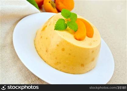 Dessert panna cotta cheesecake with apricots in a plate, mint on a napkin on the background of a brown granite table