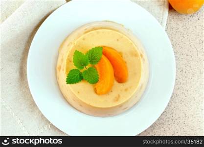 Dessert panna cotta cheesecake with apricots in a white plate, mint on a napkin, fruit on the background of a granite table top
