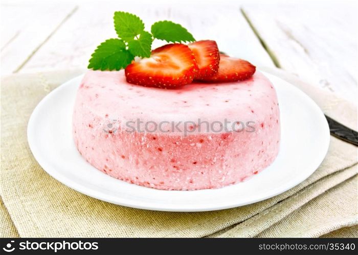 Dessert panna cotta of curd and strawberry, mint and berries in a plate on a napkin against the background of wooden boards