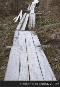 Destroyed wooden footway with hoarfrost in ravine