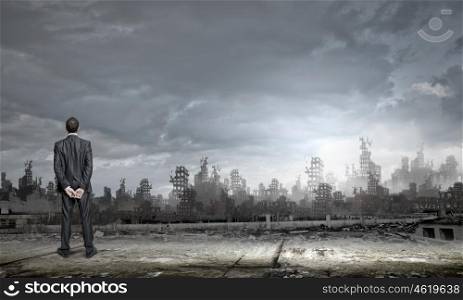 Destruction concept. Rear view of businessman looking at ruins of city