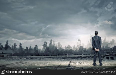 Destruction concept. Rear view of businessman looking at ruins of city