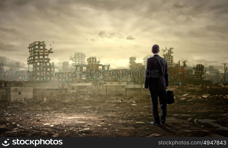 Destruction concept. Rear view of businessman looking at ruins of city