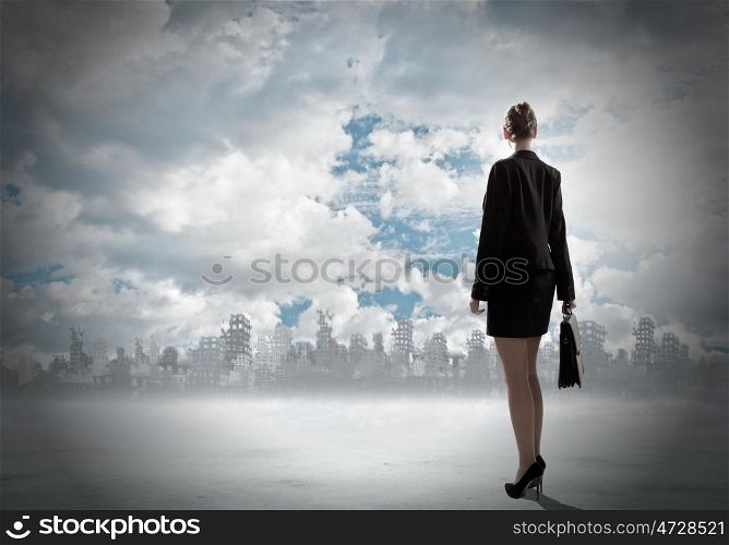 Destruction concept. Rear view of businesswoman looking at ruins of city