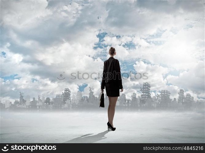 Destruction concept. Rear view of businesswoman looking at ruins of city