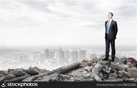 Destruction concept. Young businessman standing on ruins of building