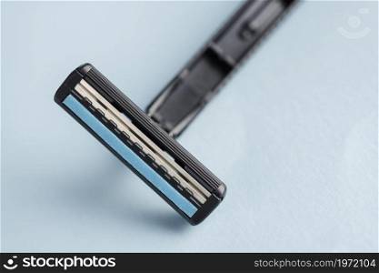 detail disposable black razor against blue backdrop. High resolution photo. detail disposable black razor against blue backdrop. High quality photo