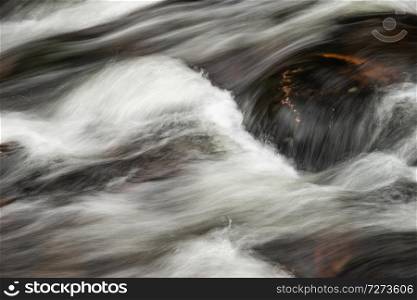 Detail landscape image of river flowing over rocks with long exposure motion blur