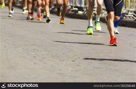 Detail of a group of runners during a city marathon. Legs and sneakers. Muscles under stress. Sport concept