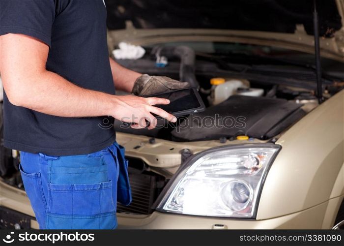 Detail of a mechanic with a digital tablet, car in background