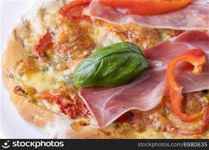 detail of a pizza with ham and basil