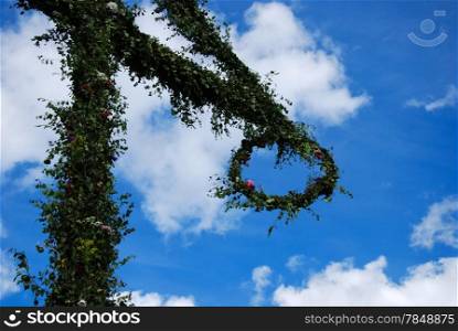 Detail of a swedish midsummer pole at blue sky with white clouds