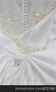 Detail of a white bridal gown or wedding dress with pearls and white buttons