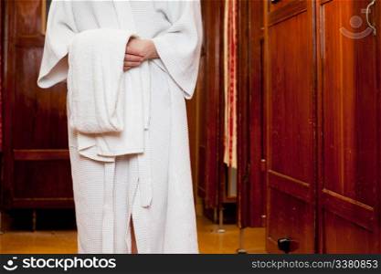 Detail of a woman wearing a bathrobe, holding a towel in an old european bath house and spa