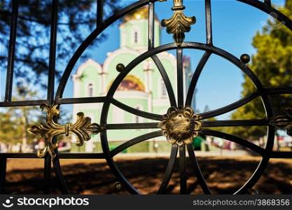 Detail of a wrought-iron fence on the background of the church in the village