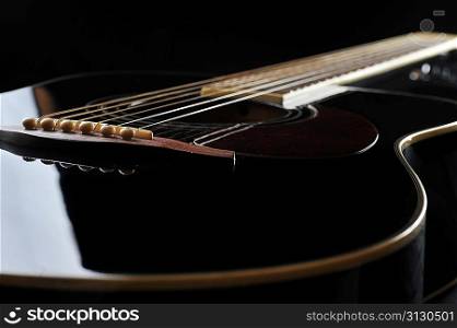 Detail of an acoustic black guitar with the strings and the sound hole