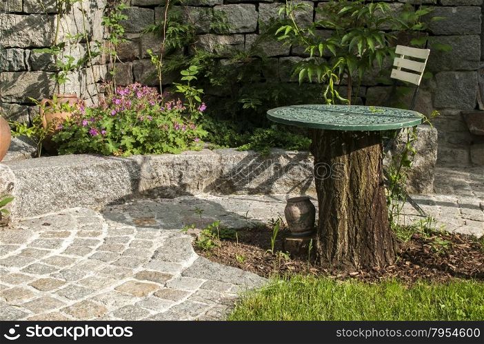 Detail of back yard garden with table, chair and pavement