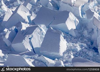 Detail of blocks of ice and snow on a shimmering blue glacial tongue in Antarctica