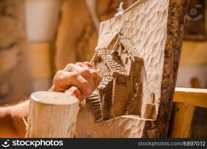 Detail of caucasian middle aged scultor working on wood, natural daylight