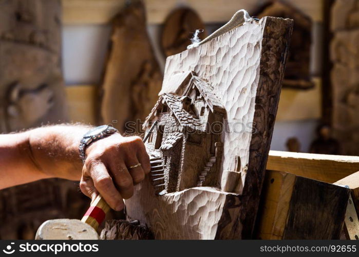 Detail of caucasian middle aged scultor working on wood, natural daylight