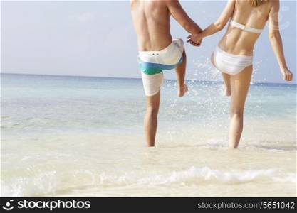 Detail Of Couple Splashing In Sea On Beach Holiday