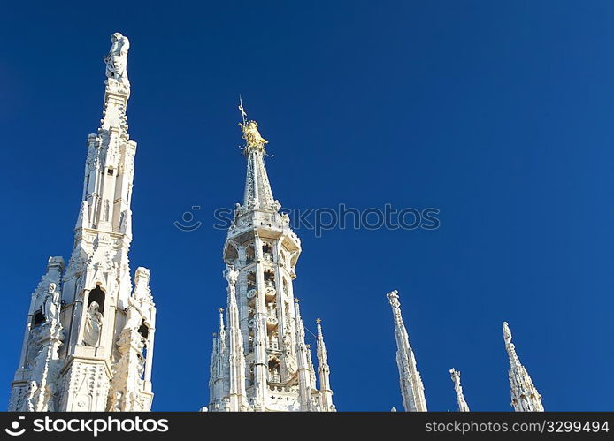 Detail of Duomo di Milano (Milan Cathedral) with the famous &acute;Madonnina&acute; (the symbol of Milano) atop the main spire of the cathedral, a baroque gilded bronze artwork.