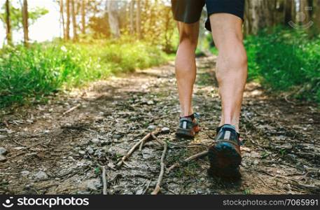 Detail of feet of young man participating in a trail race through the forest. Feet of man participating in trail race