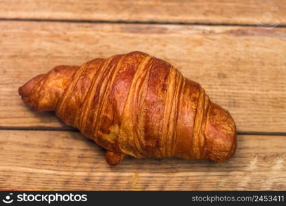 Detail of fresh croissant on wooden table. Food and breakfast concept. Top view and copy space. Detail of fresh croissant on wooden table. Food and breakfast concept. Top view and copy space