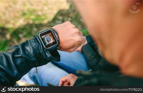 Detail of hand of unrecognizable young man talking by videoconference with his smartwatch. Unrecognizable man talking by videoconference with his smartwatch