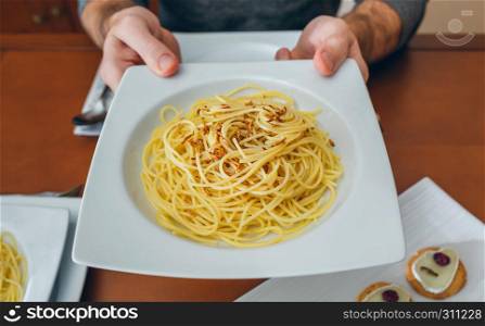 Detail of hands of unrecognizable man showing spaghetti with crispy worms dish. Hands of man showing spaghetti with worms dish