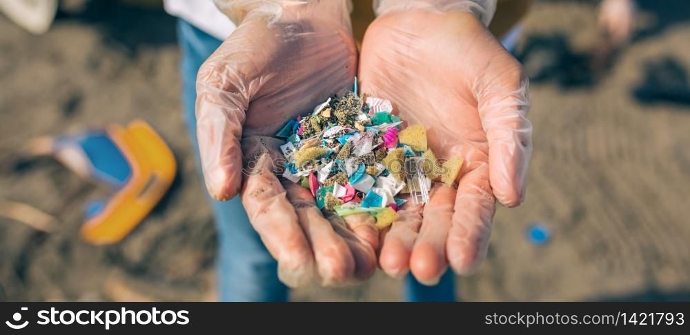 Detail of hands showing microplastics on the beach. Hands with microplastics on the beach