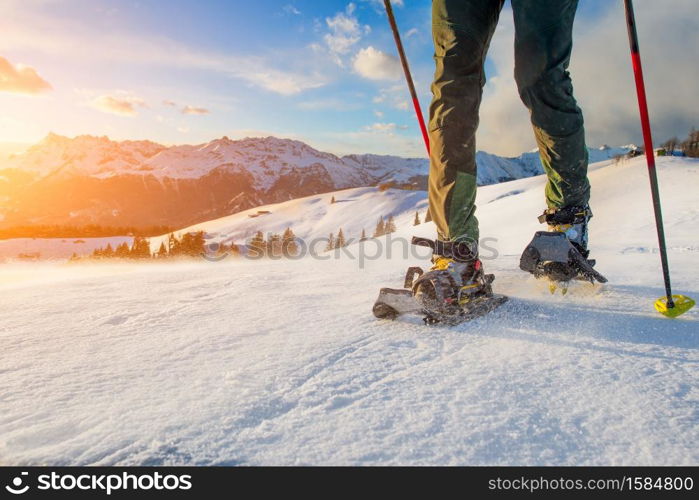 Detail of man walking with technical snowshoes in mountains