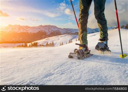 Detail of man walking with technical snowshoes in mountains