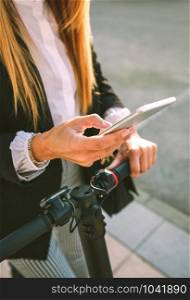 Detail of mobile of businesswoman with electric scooter in the street