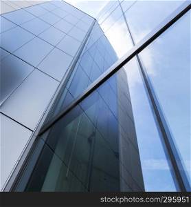 detail of modern corporate office building with glass and steel reflecting blue sky and clouds